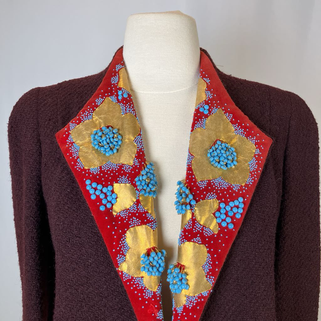 Mannequin wearing a brown jacket with a decorative red and gold floral scarf.