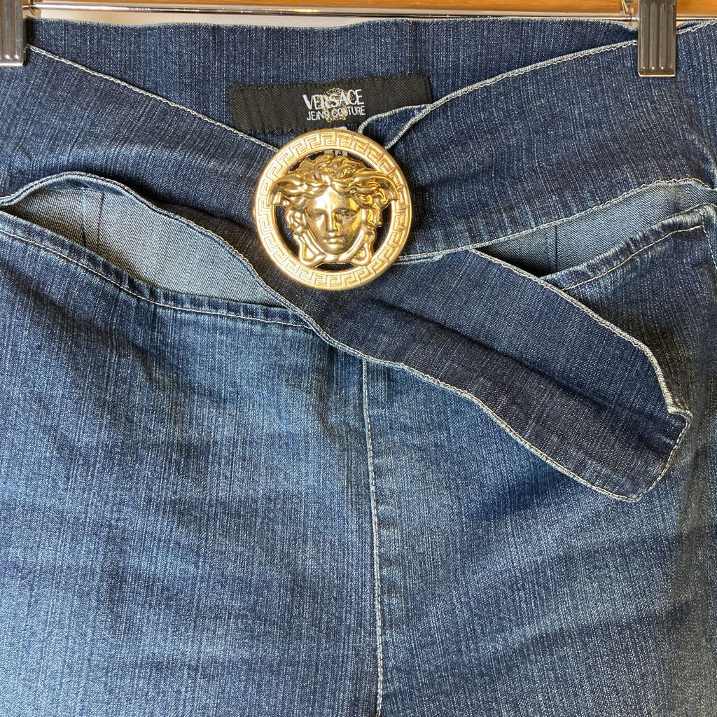 Blue jeans with a gold Versace belt buckle on a hanger
