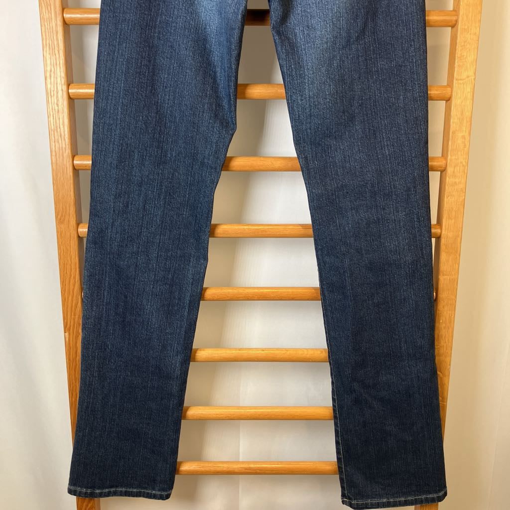 Blue jeans hanging on a wooden rack against a white wall
