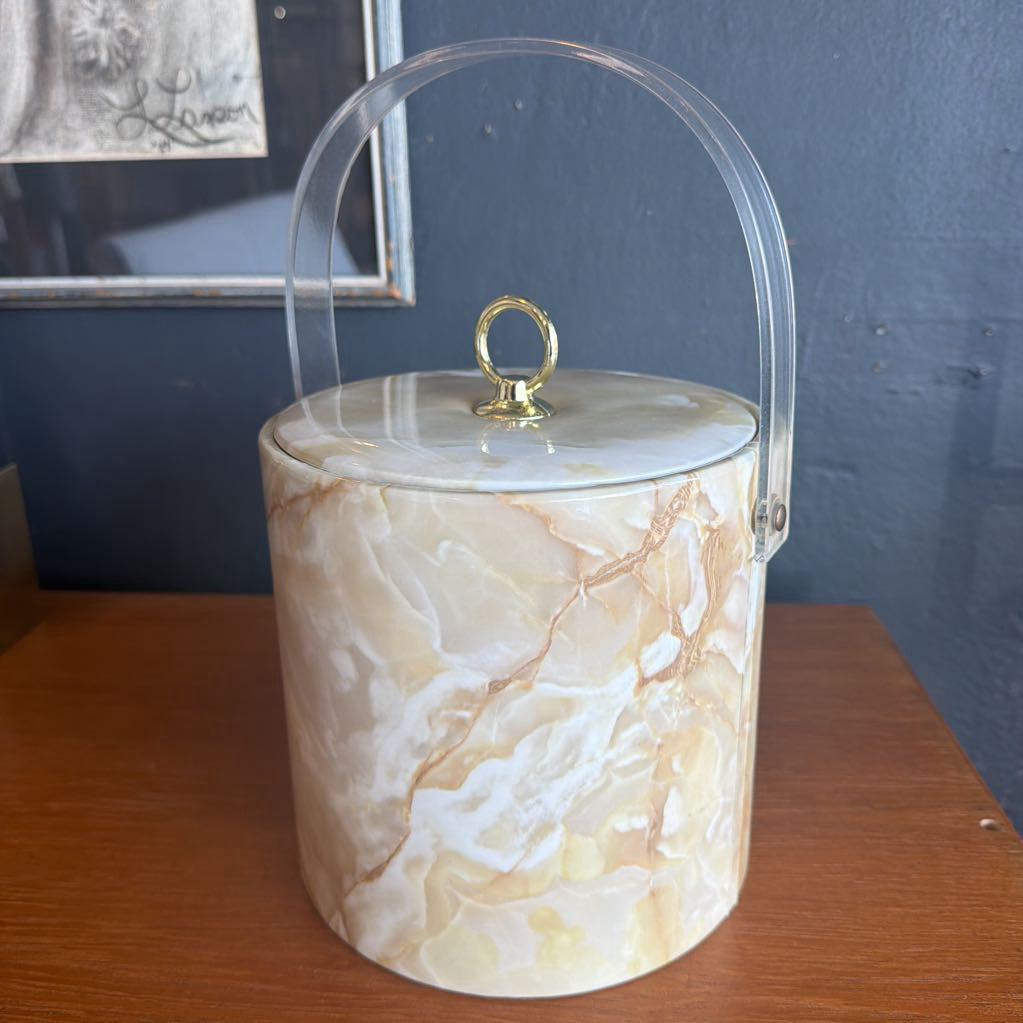 Marble-patterned container with a gold handle on a wooden surface.