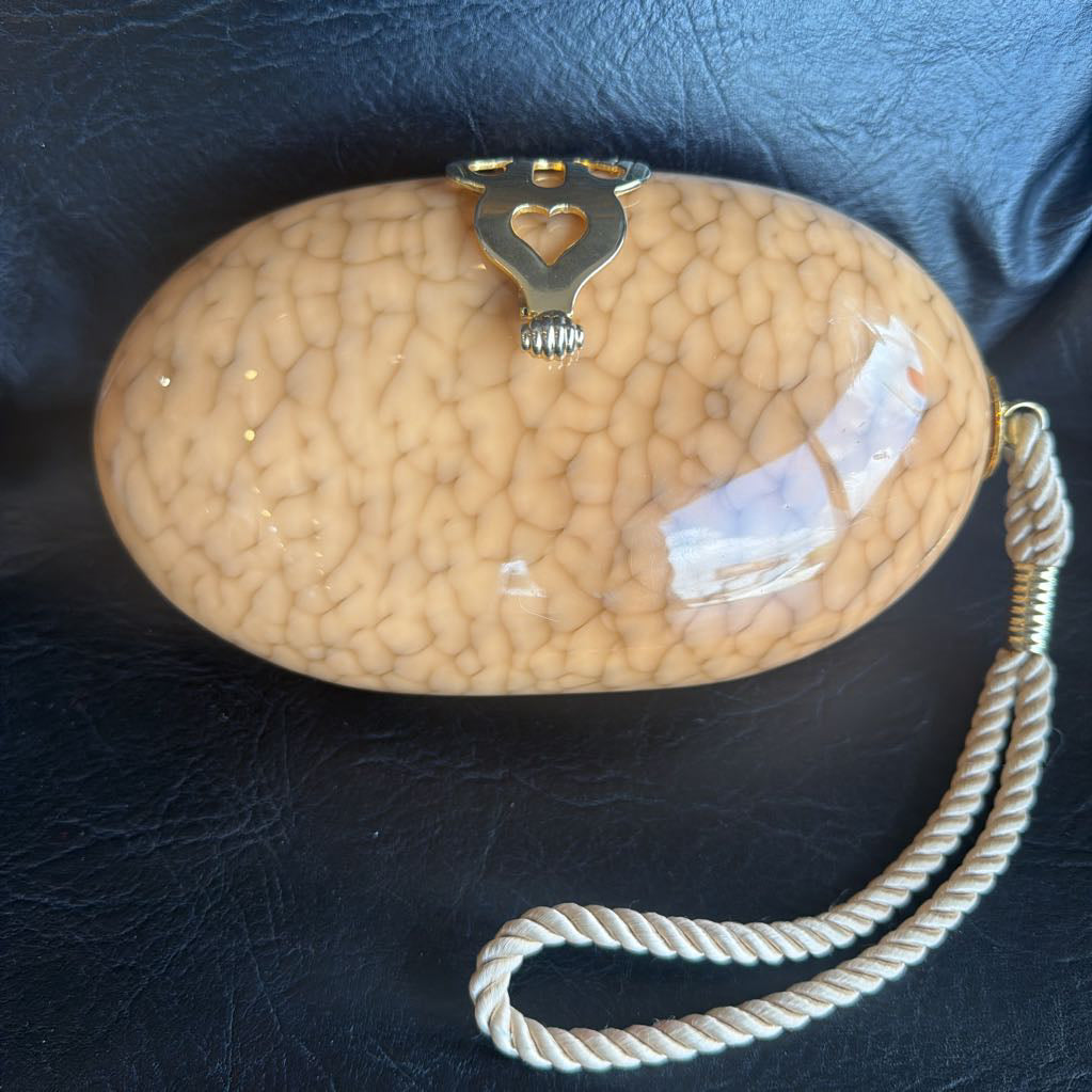 Beige textured handbag with a heart-shaped clasp on a dark blue background