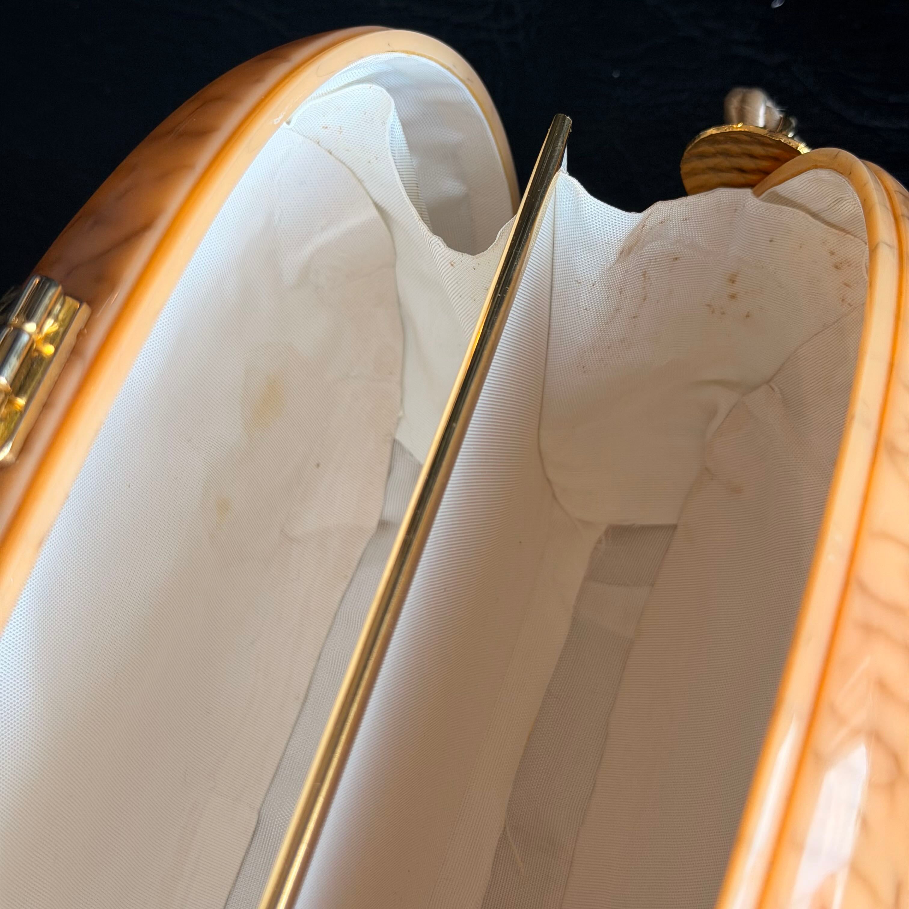 Close-up of a beige handbag with gold accents on a black background