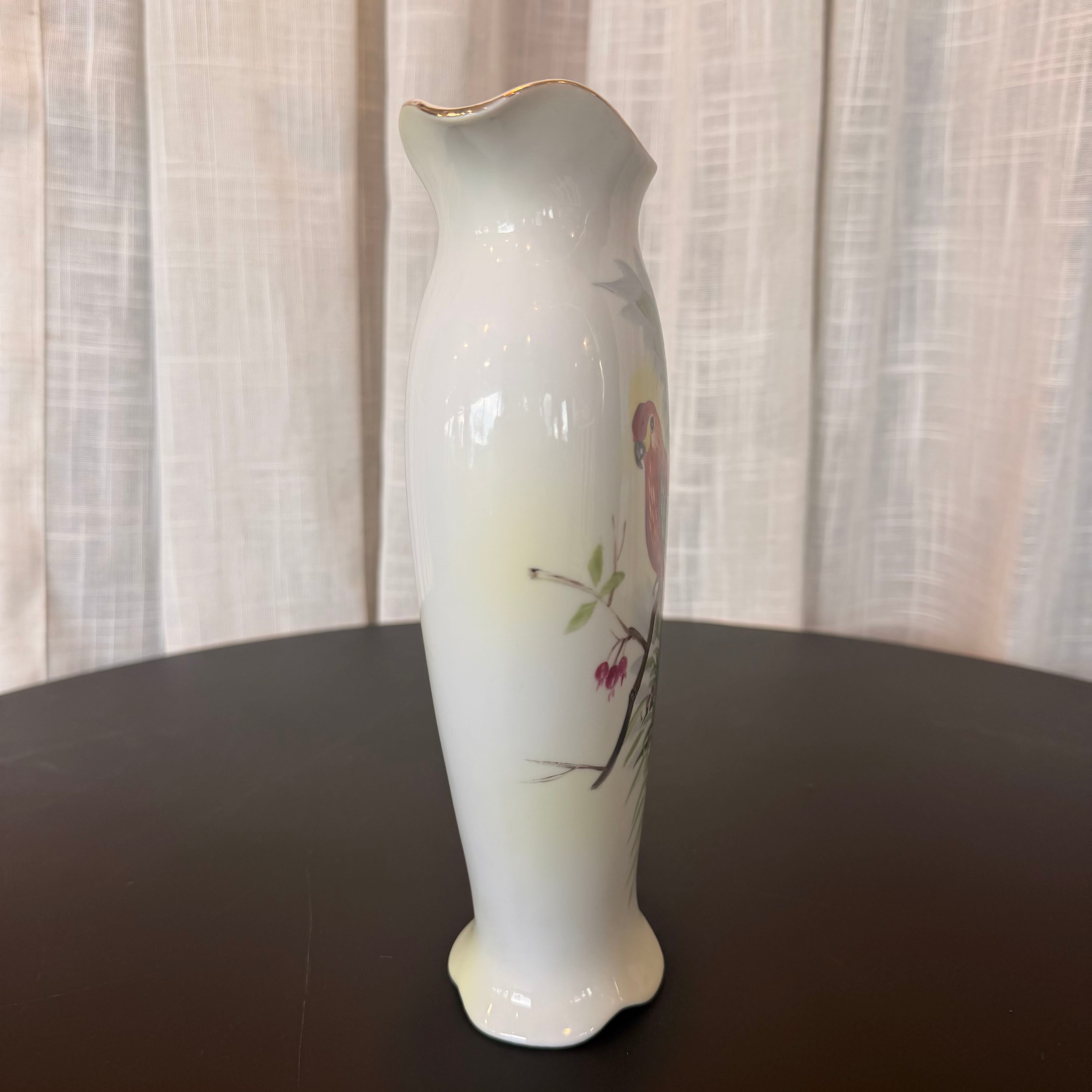 White ceramic vase with floral design on a dark surface and light curtain background