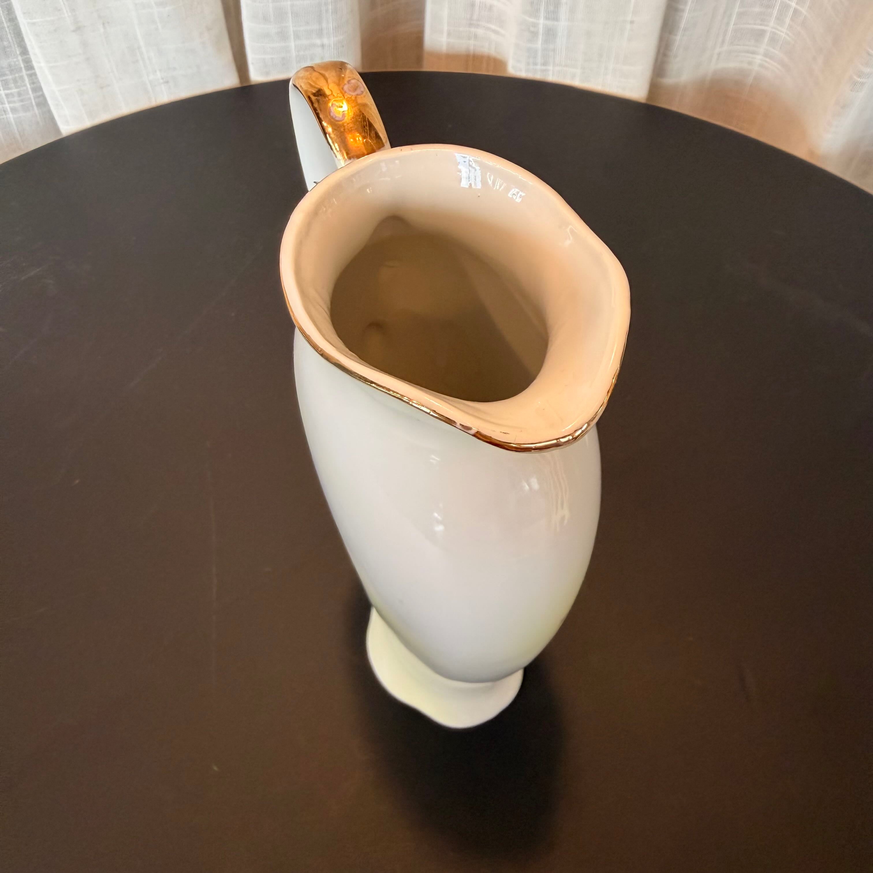 White ceramic cup with gold rim on a dark surface
