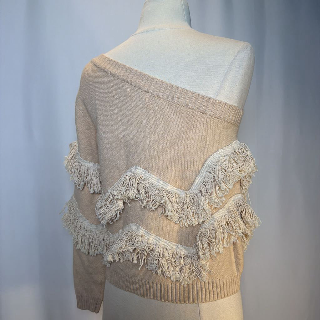 Beige sweater with fringe details on a mannequin against a plain background
