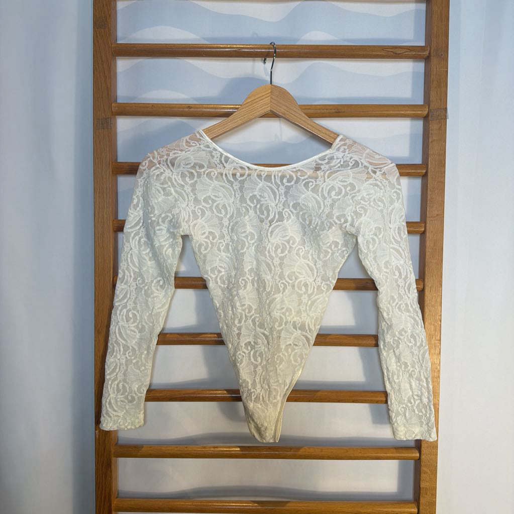 Lace top on a wooden hanger against a wooden ladder with a cloudy sky background