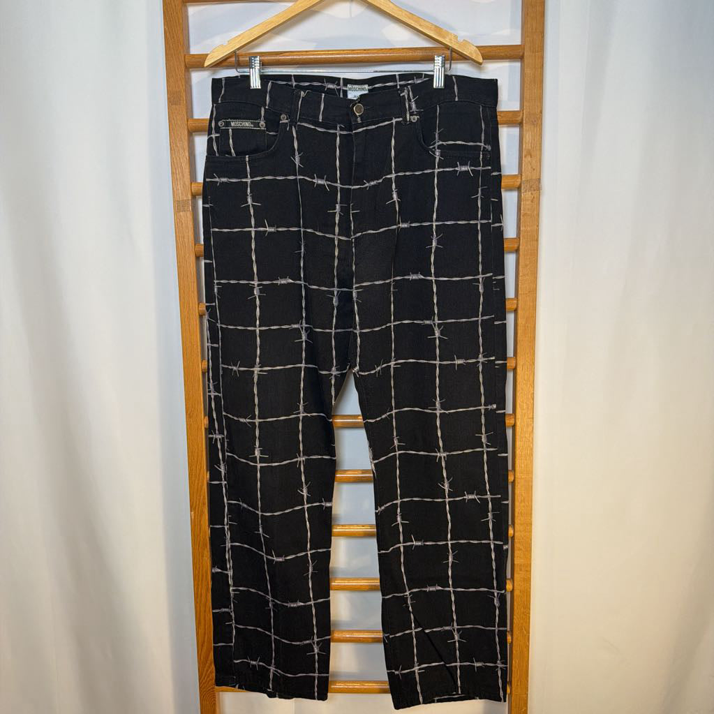 Black checkered pants on a wooden hanger against a white background