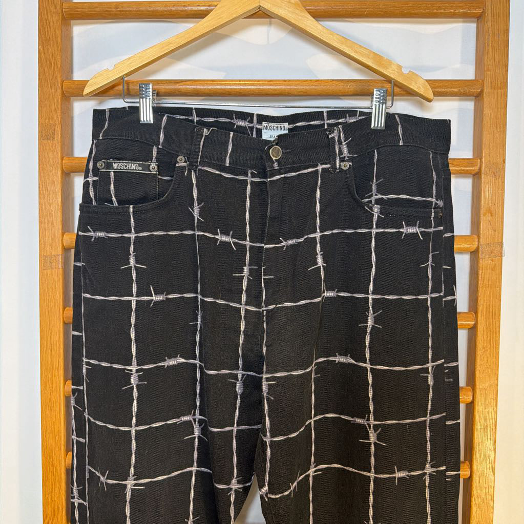 Black pants with white grid pattern on a wooden hanger against a white background