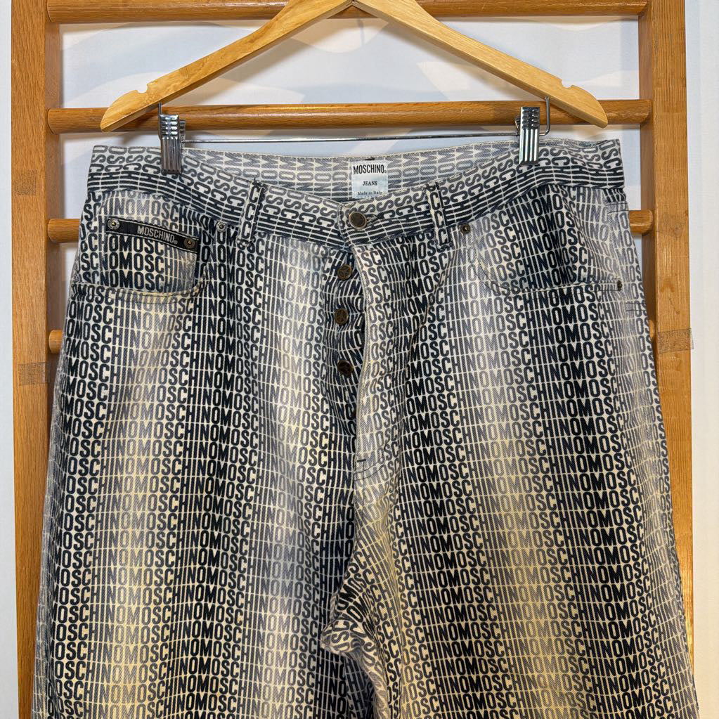 Black and white patterned shorts with 'Moschino' branding on a wooden hanger.