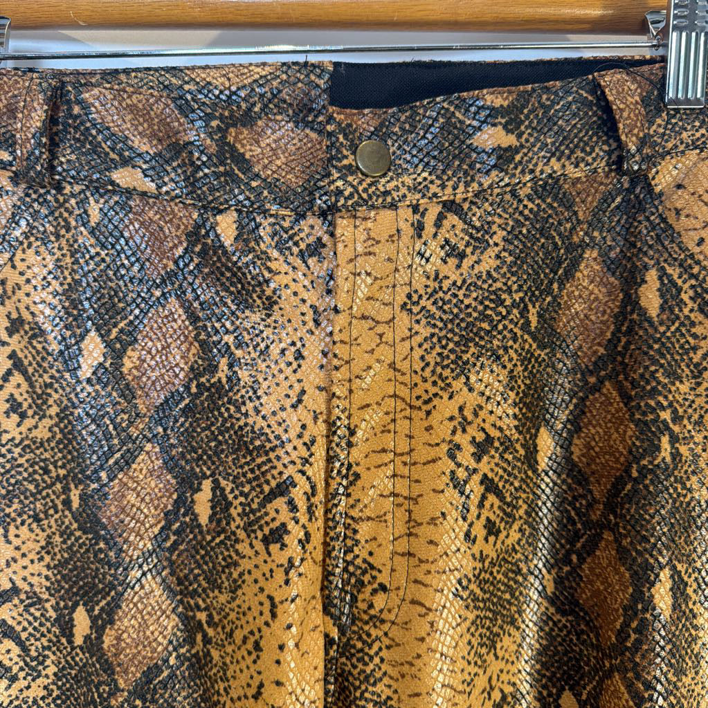Close-up of a snake print pants with a button on a wooden surface.