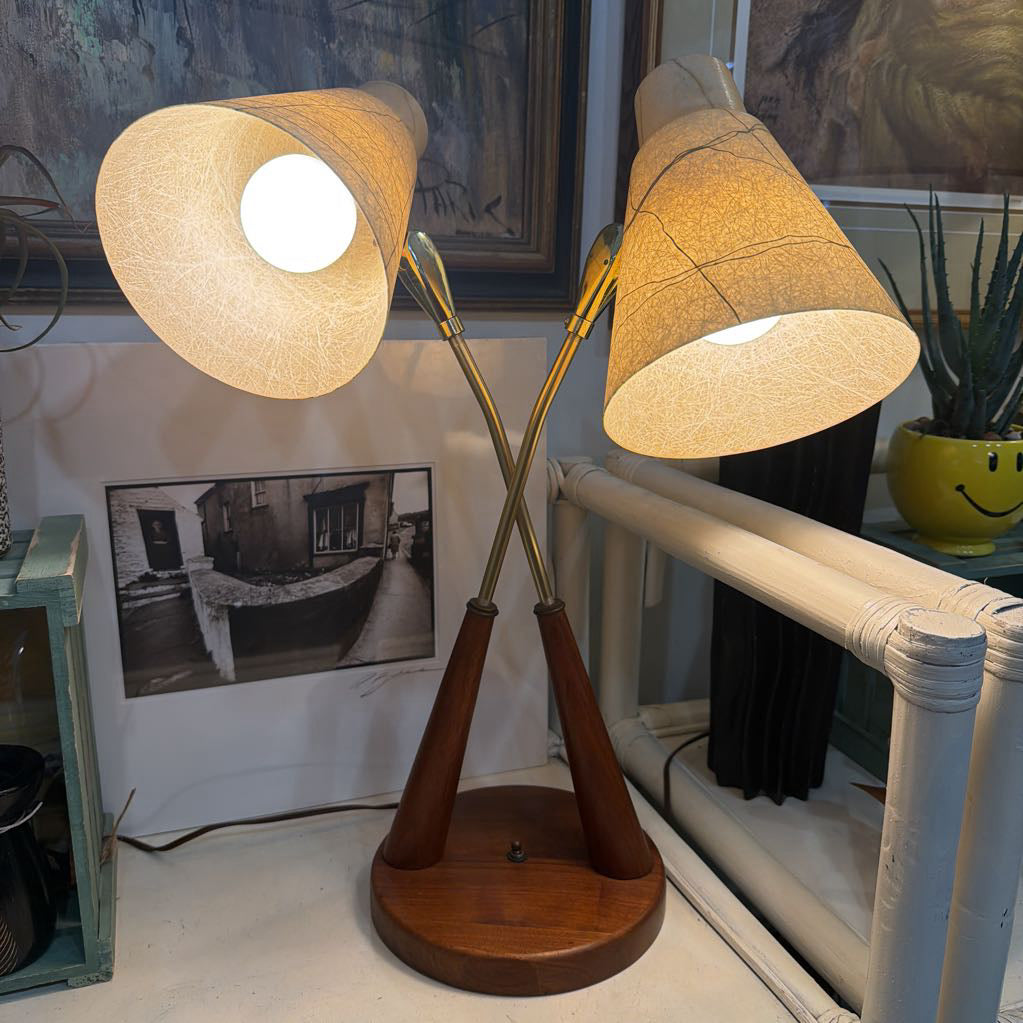 Vintage-style double lamp with wooden base and fabric shades on a surface.