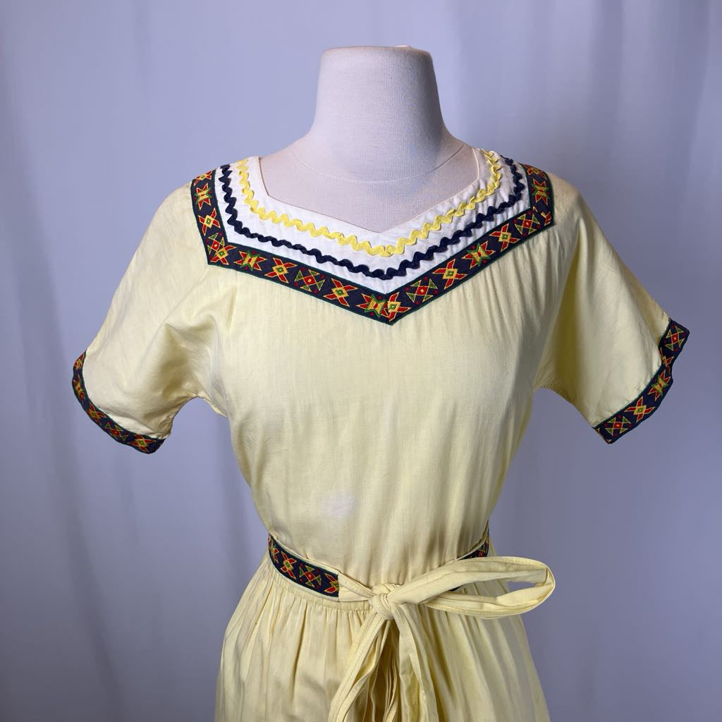 Beige dress with colorful embroidery on a mannequin against a plain background