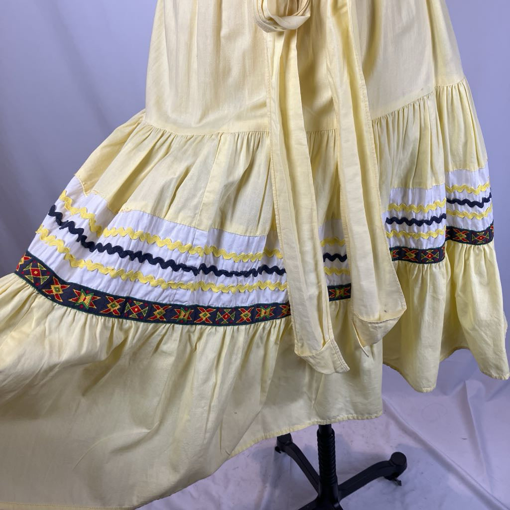 Yellow dress with decorative hem on a mannequin against a light purple background