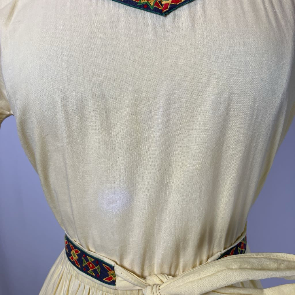 White dress with colorful embroidery on a plain background