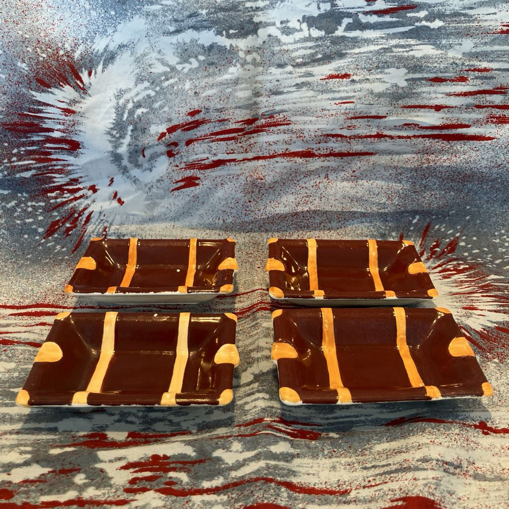 4 brown small dishes with gold stripes on a textured surface with red and blue abstract patterns.