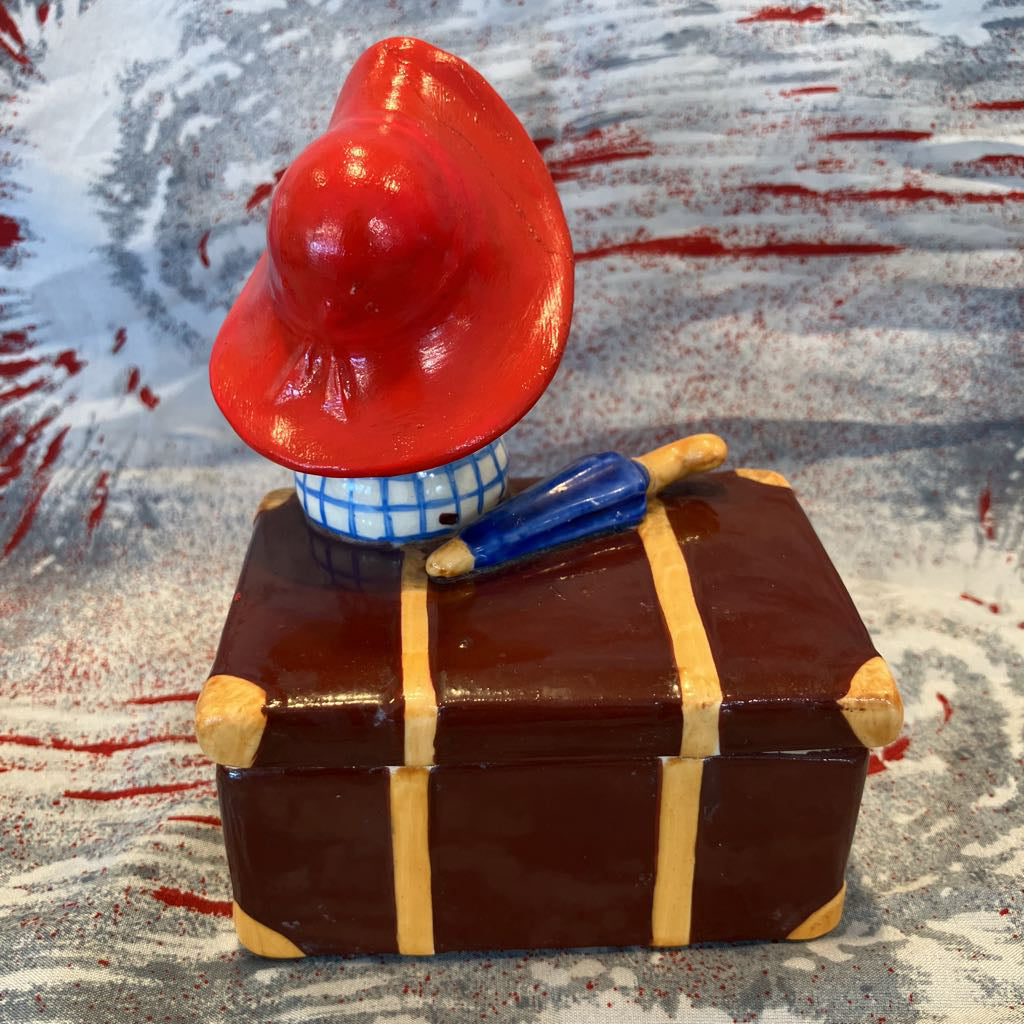 Decorative figure of a girl with a red hat on a suitcase against a patterned background