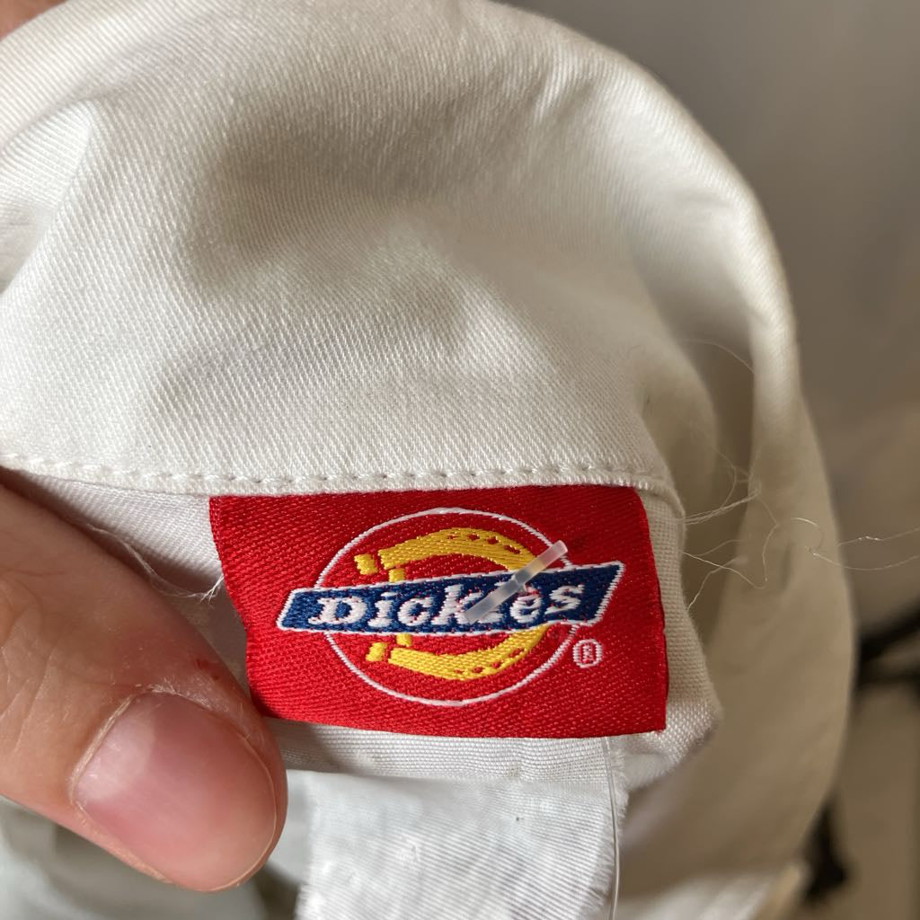 Dickies logo on a white cap with a hand holding it