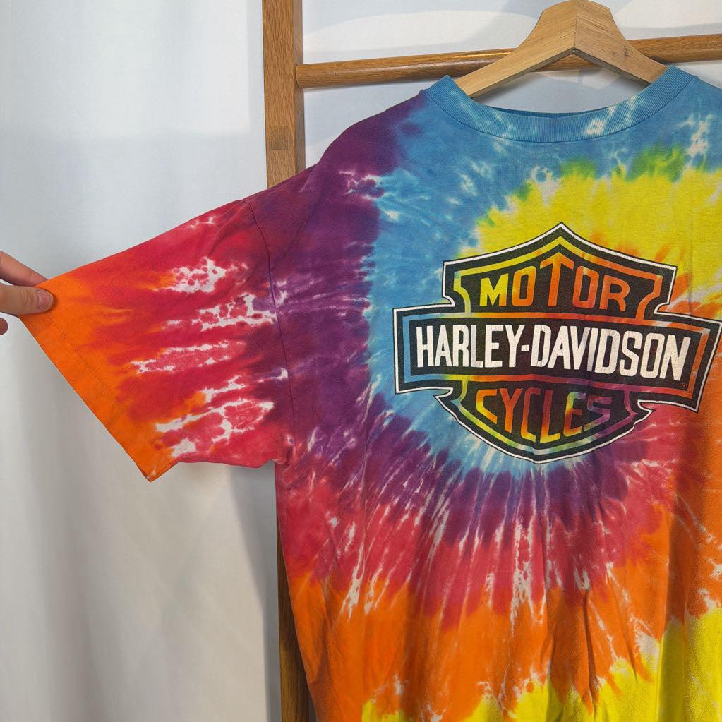 Tie-dye t-shirt with Harley-Davidson logo on a hanger against a white background