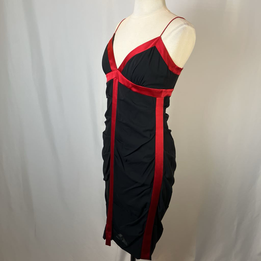 Black dress with red straps on a mannequin against a plain background