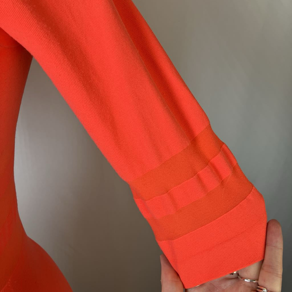Close-up of an orange sweater sleeve with a blurred background