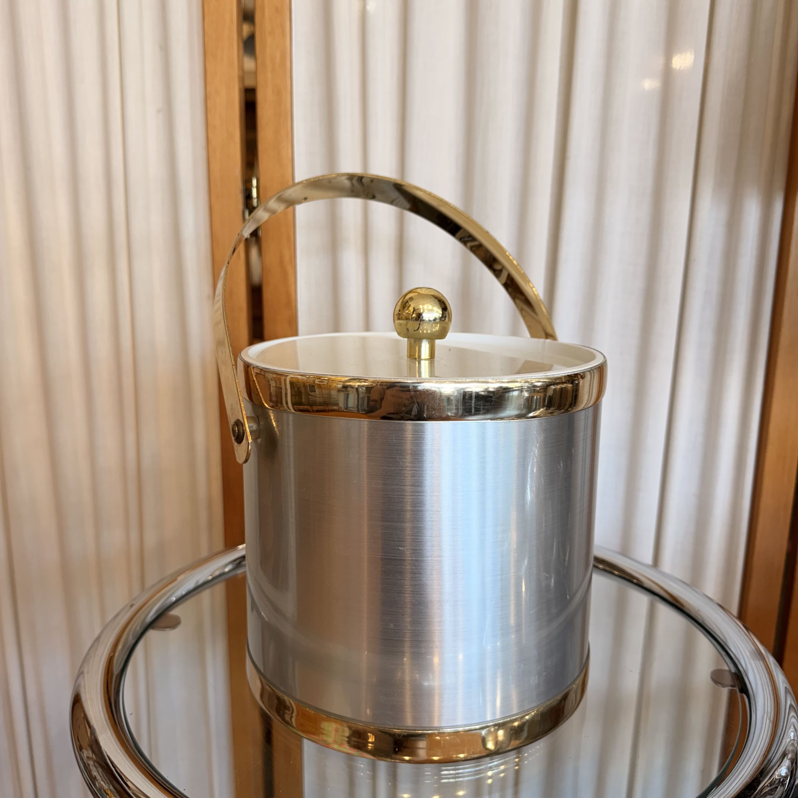 Silver ice bucket with gold accents on a reflective surface