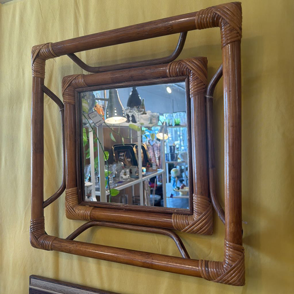 Square rattan-framed mirror on a yellow wall
