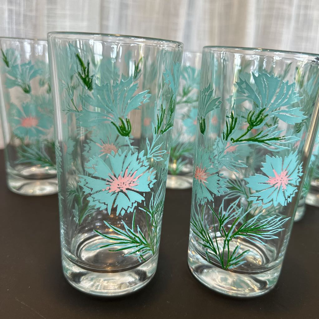Clear glasses with blue floral designs on a dark surface