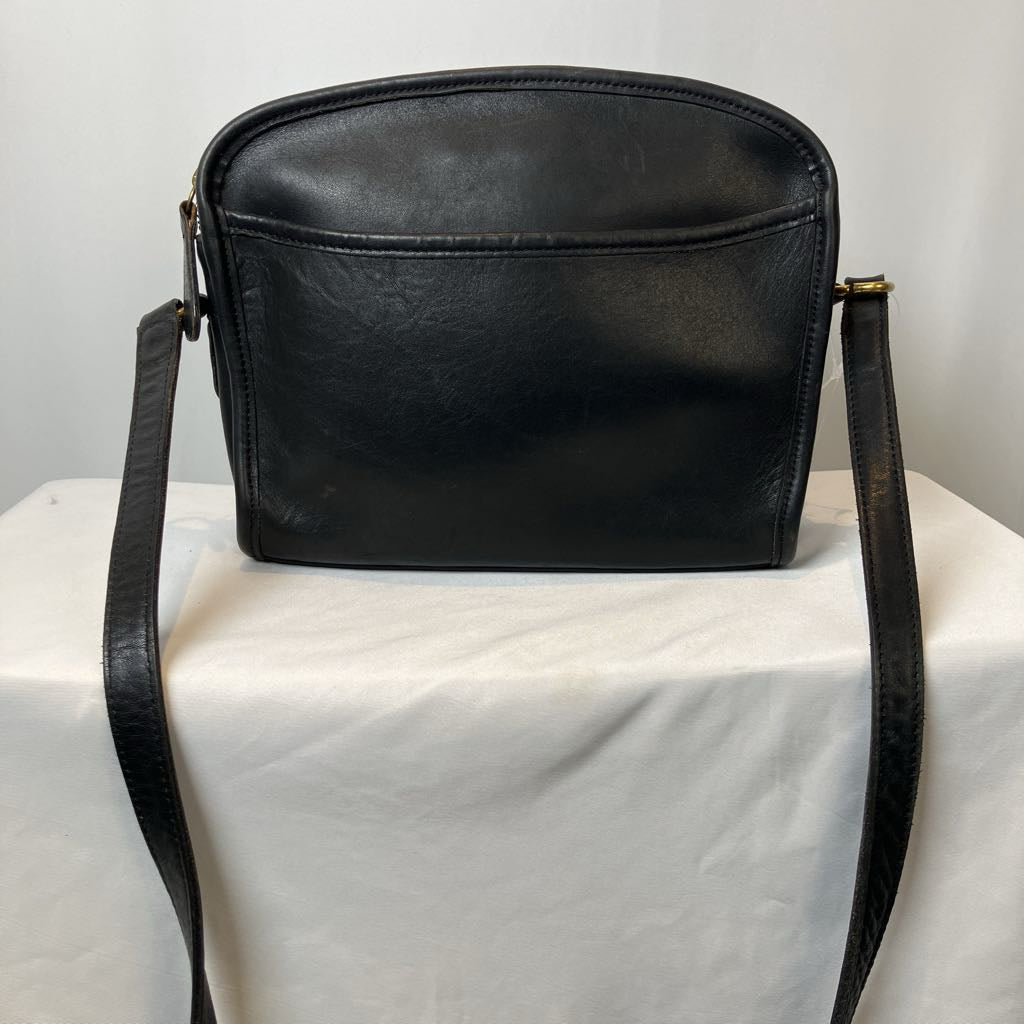 Black leather handbag on a white surface with a light gray background