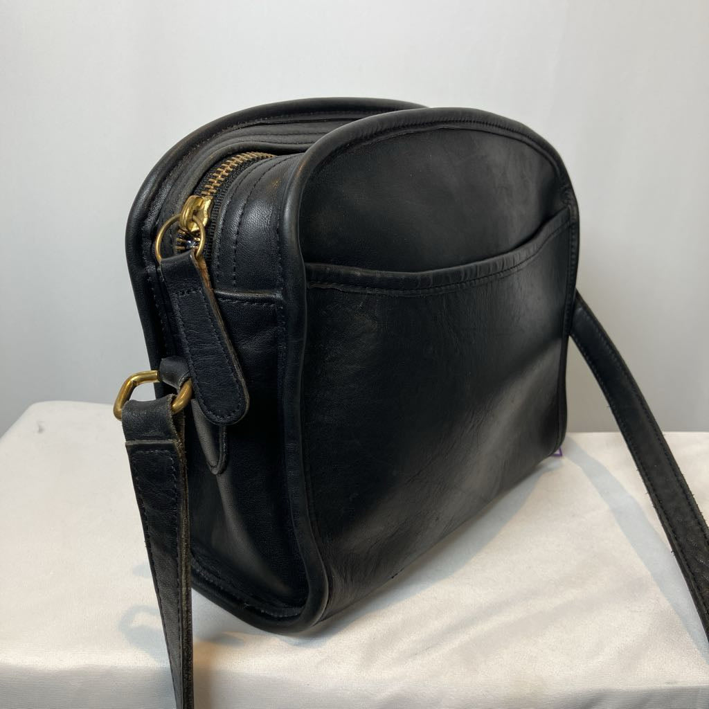 Black leather handbag with gold zippers on a white surface