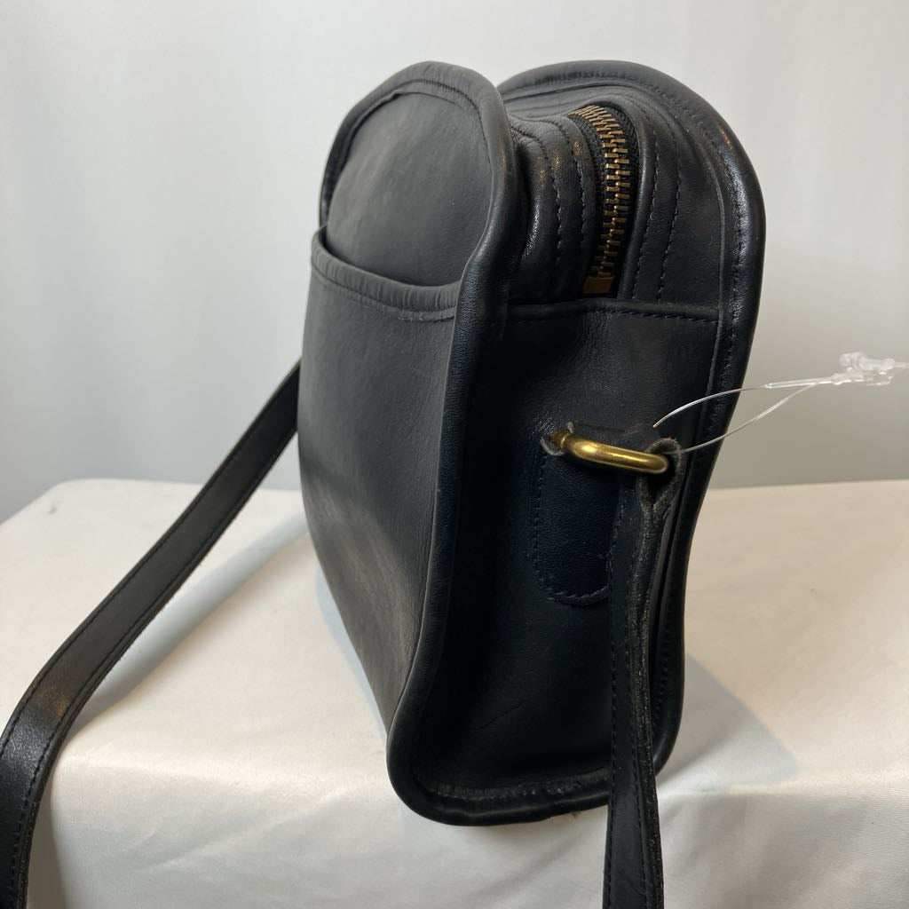 Black leather bag with gold zipper on a white surface