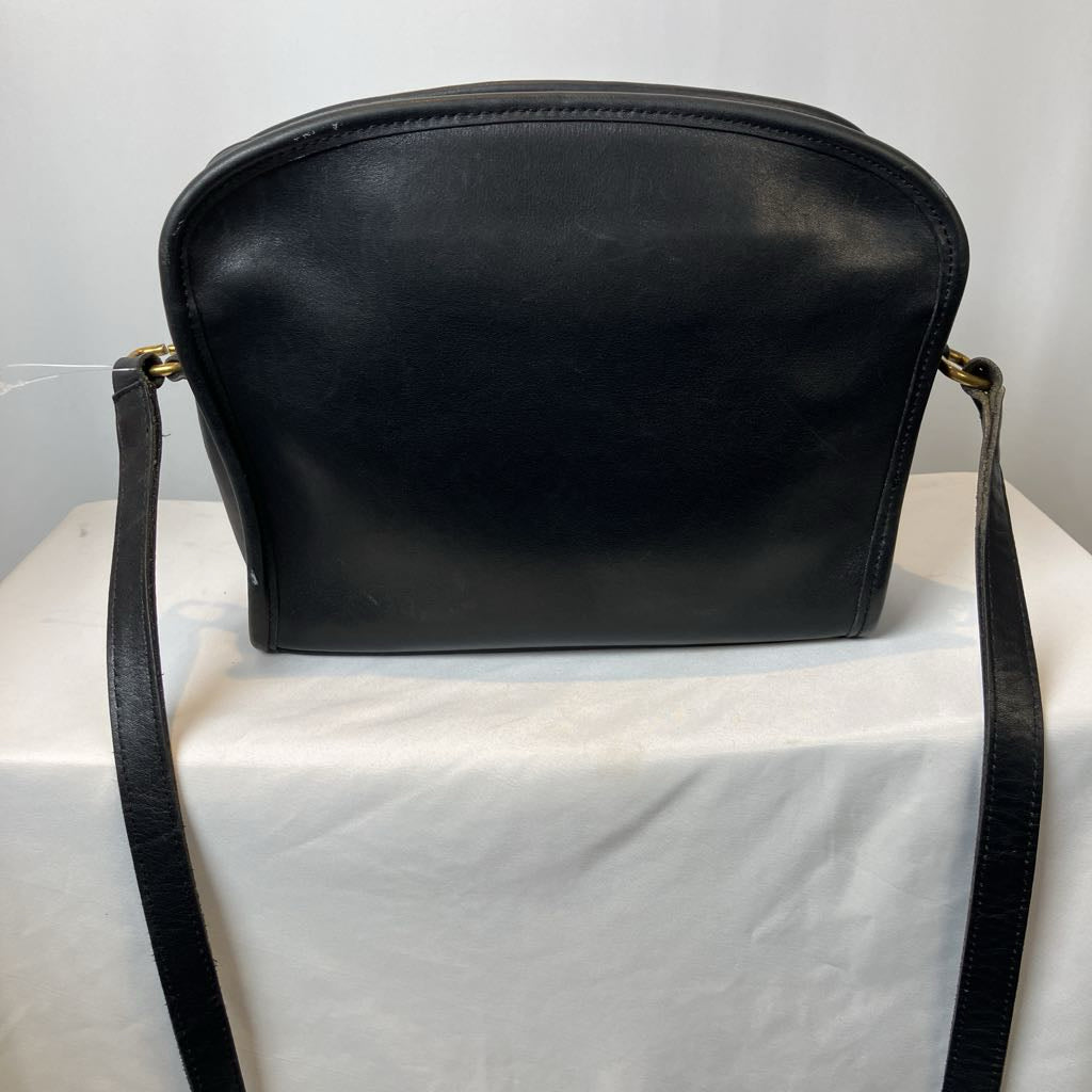 Black leather handbag on a white surface with a light gray background