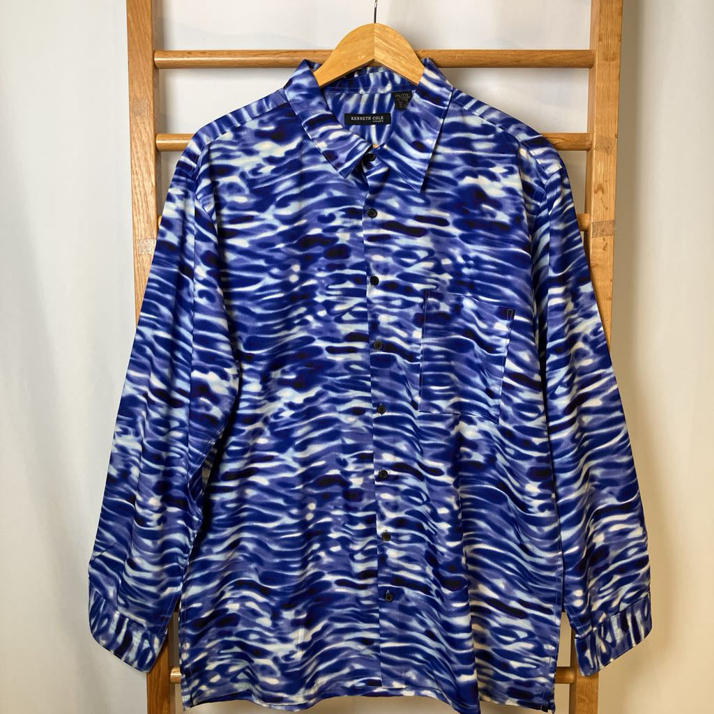 Blue and white patterned shirt on a wooden hanger against a white wall