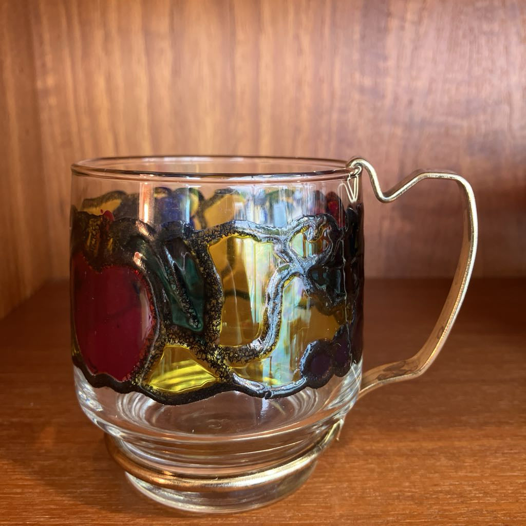 Clear glass mug with decorative handle on a wooden surface