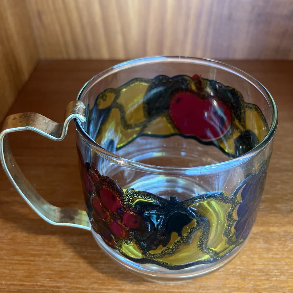 Clear glass mug with colorful fruit design on a wooden surface