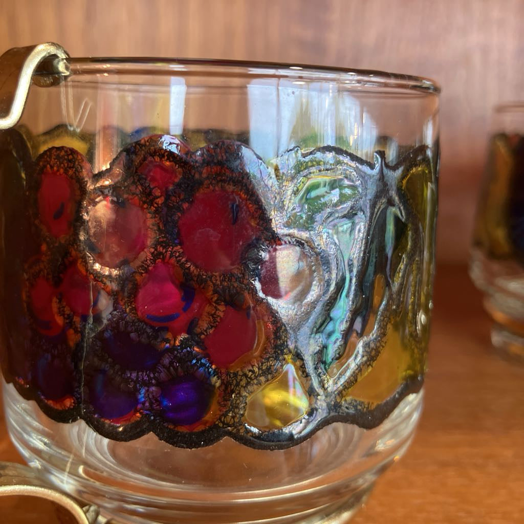 Decorative glass mug with a fruit design on a wooden surface