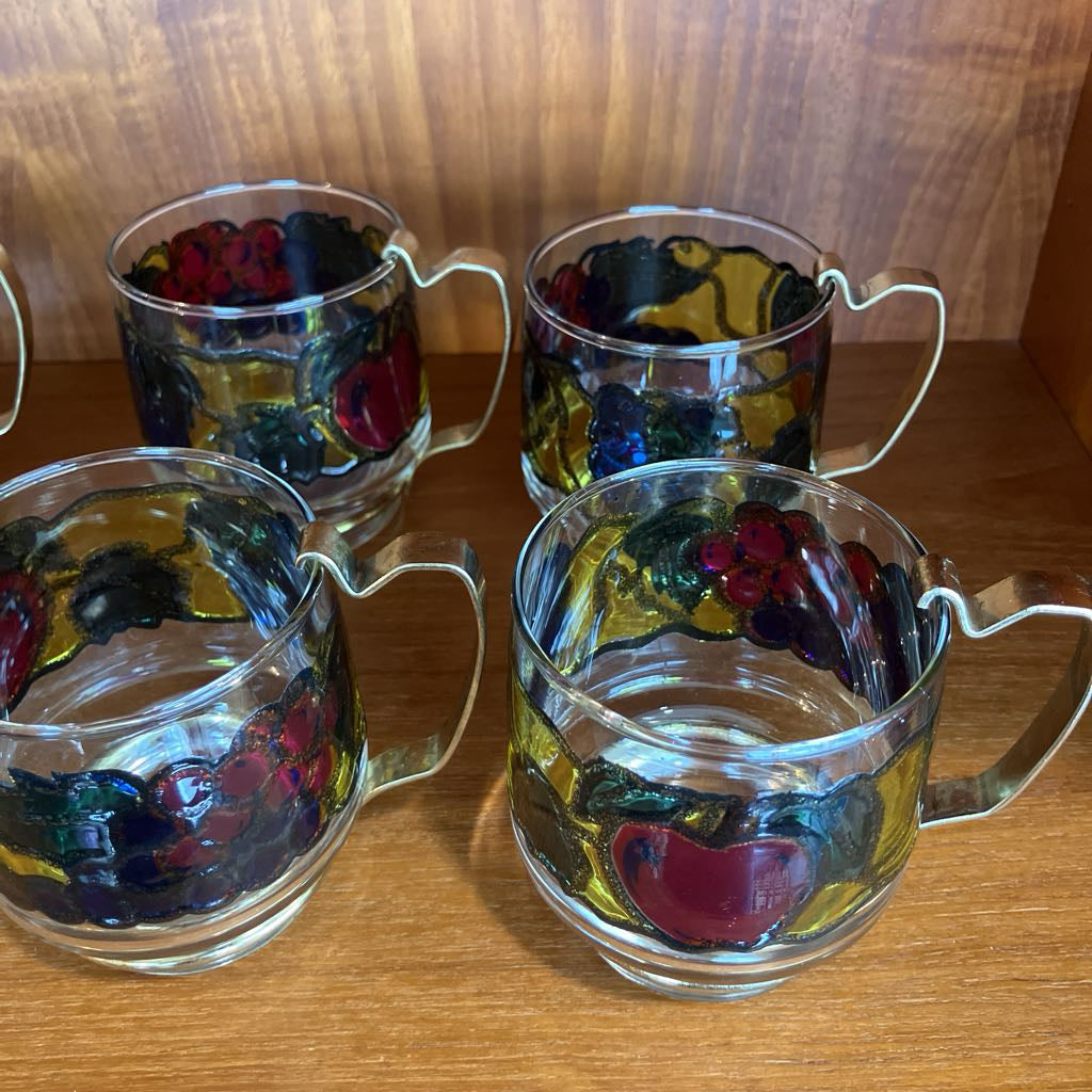 Set of four glass mugs with floral designs on a wooden surface