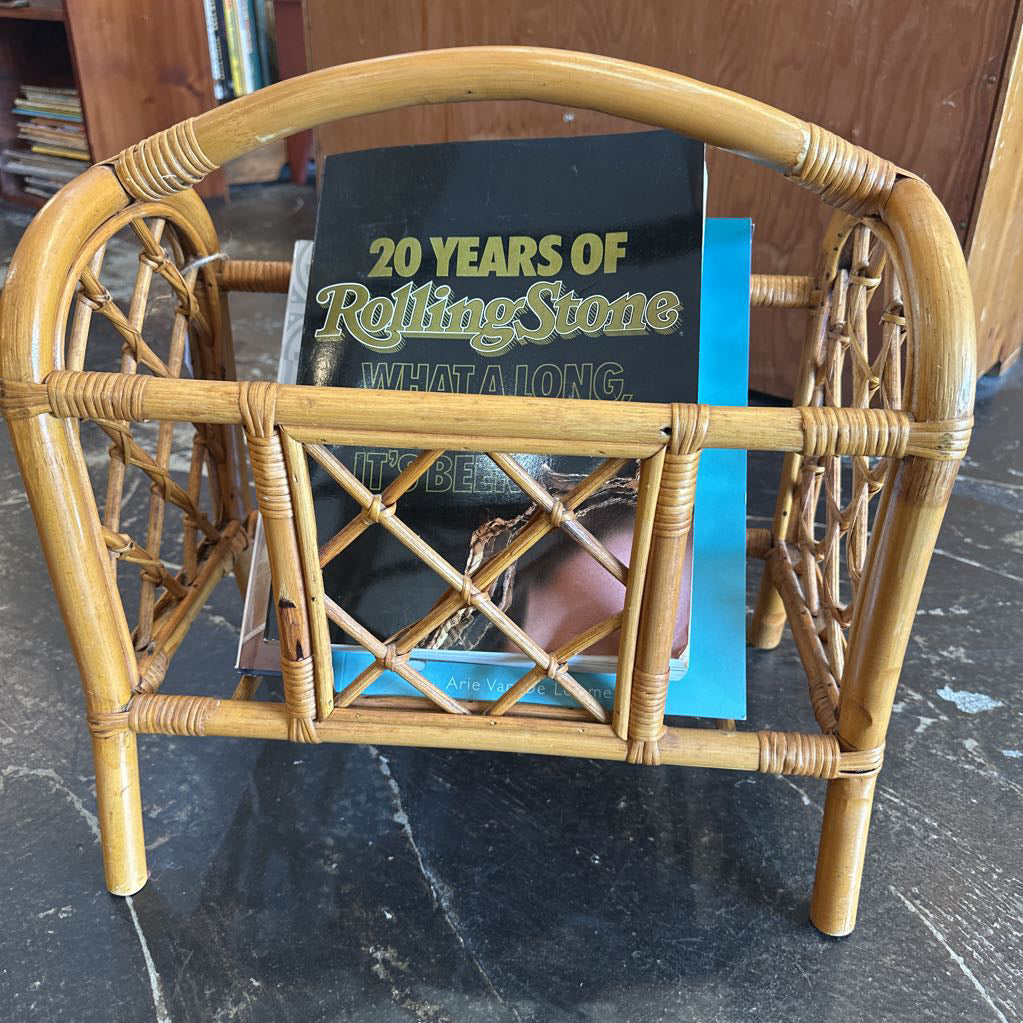 Wicker magazine holder with a book titled '20 Years of Rolling Stone' on a dark surface.