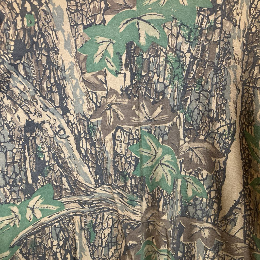 Close-up of a fabric with a nature-themed pattern featuring trees and leaves.