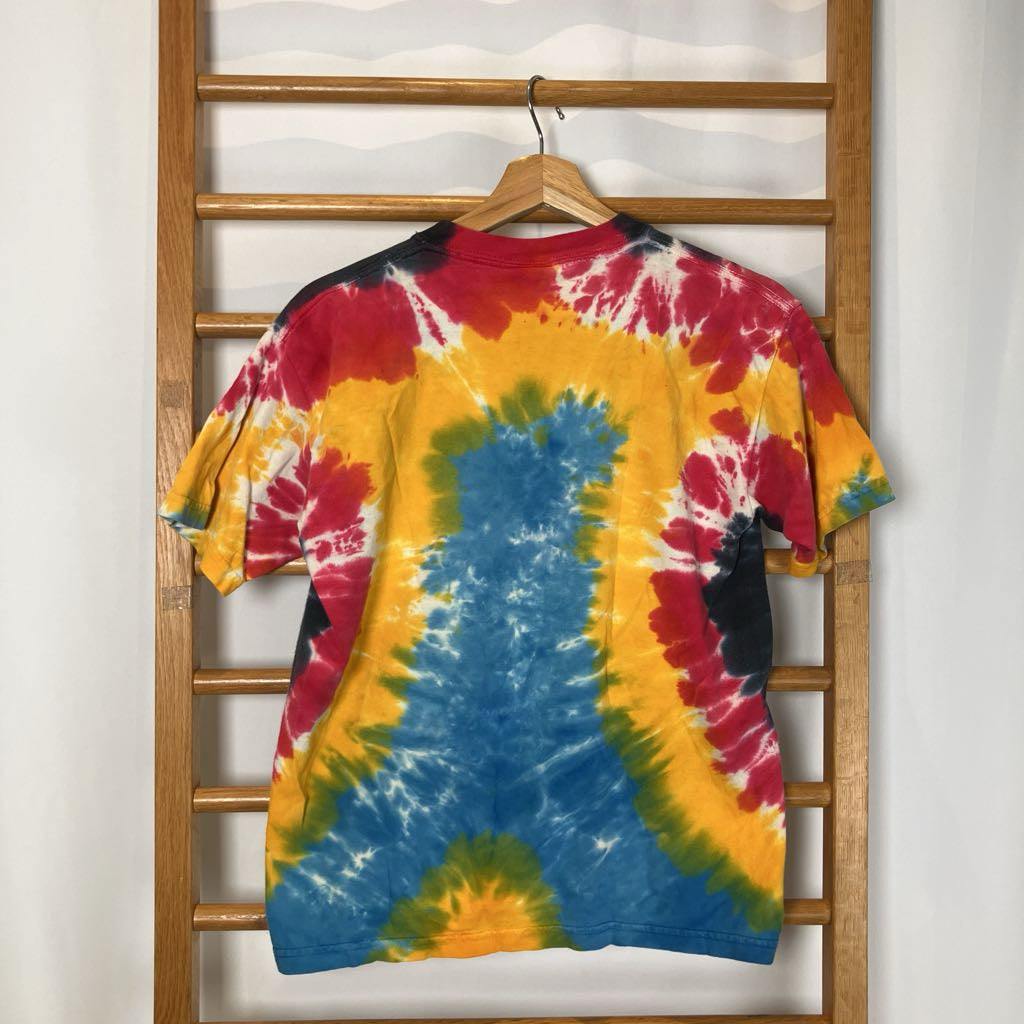 Colorful tie-dye t-shirt on a wooden hanger against a white wall.