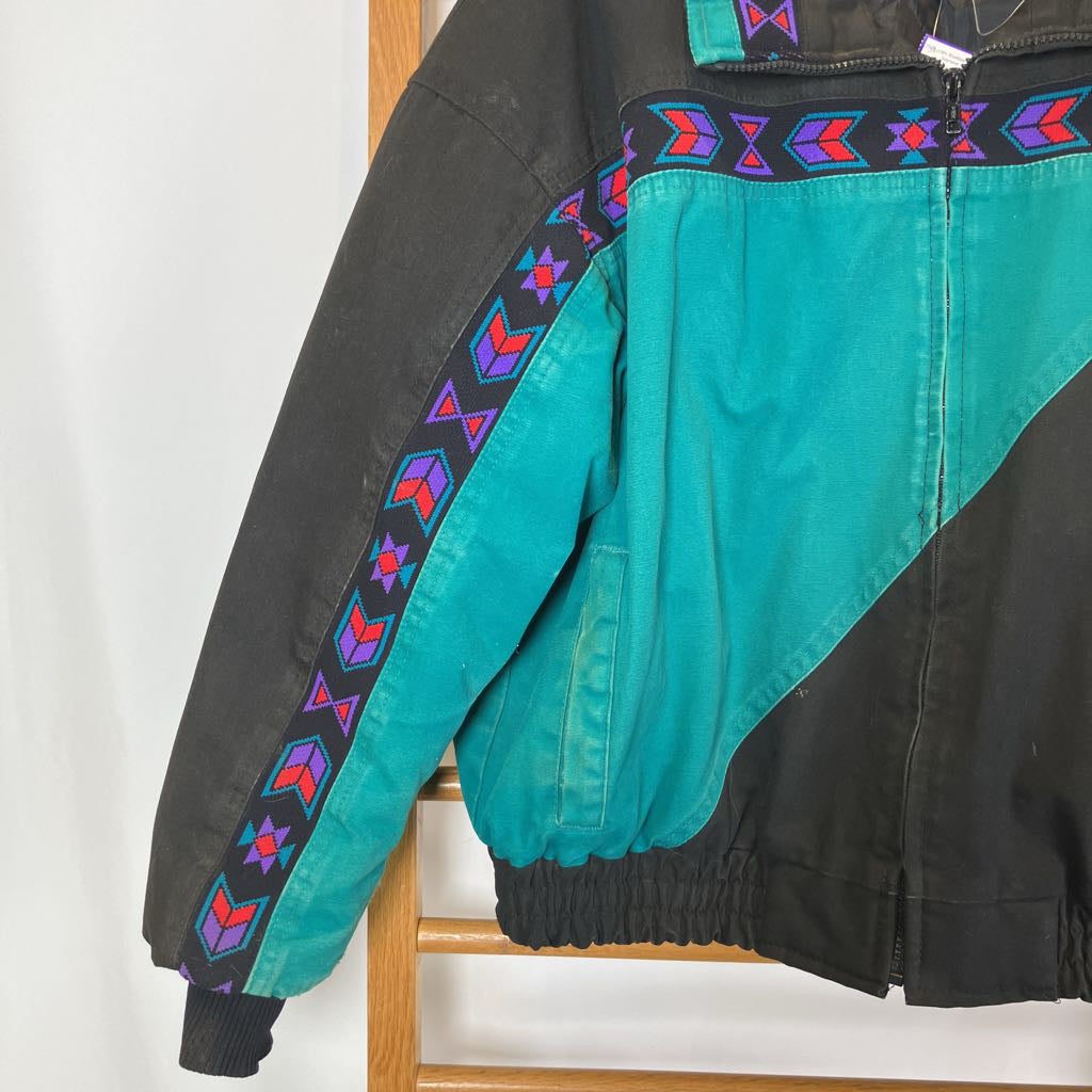 Teal and black jacket with colorful pattern on a wooden chair against a white background