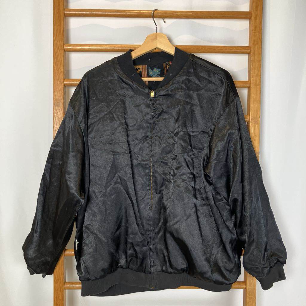 Black jacket hanging on a wooden rack against a white wall
