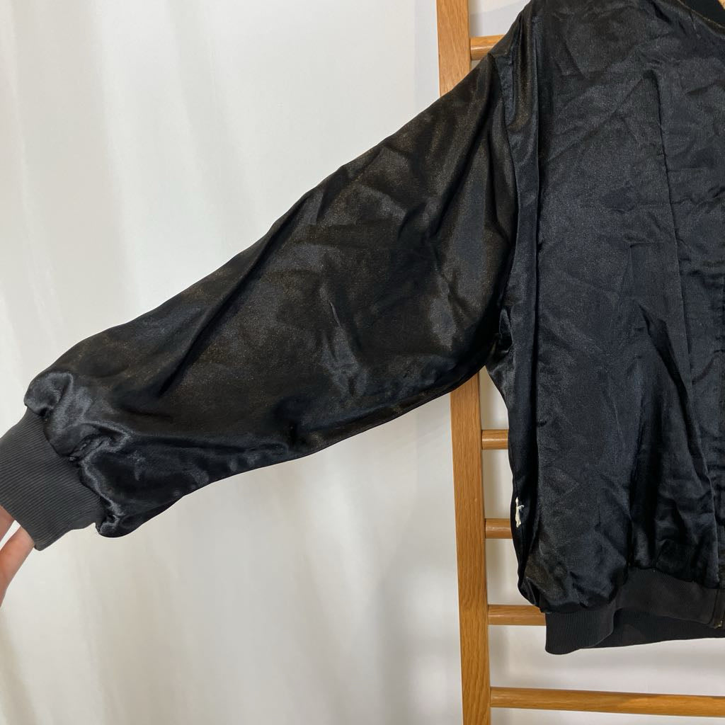 Black jacket hanging on a wooden rack against a white background