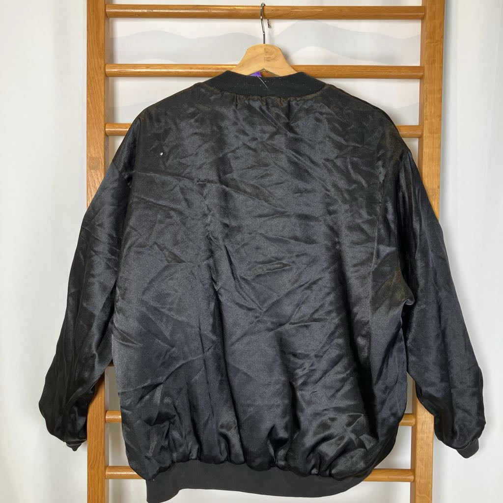 Black jacket hanging on a wooden rack against a white wall