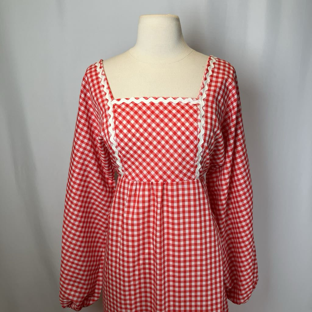Red and white checkered dress on a mannequin against a gray background