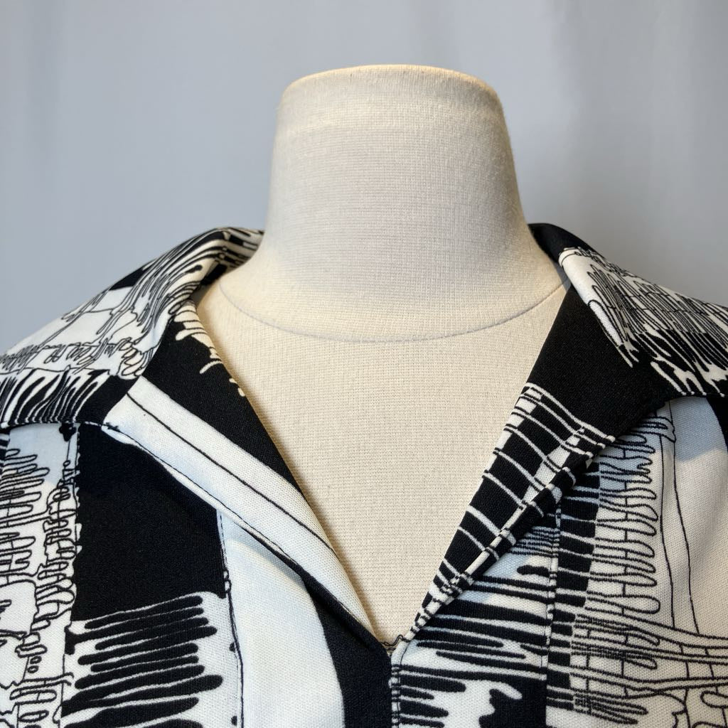 Mannequin wearing a black and white patterned jacket against a gray background
