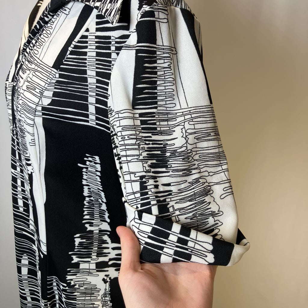 Black and white patterned fabric held by a hand against a neutral background