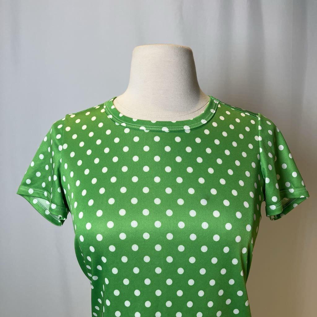 Green t-shirt with white polka dots on a mannequin against a plain background