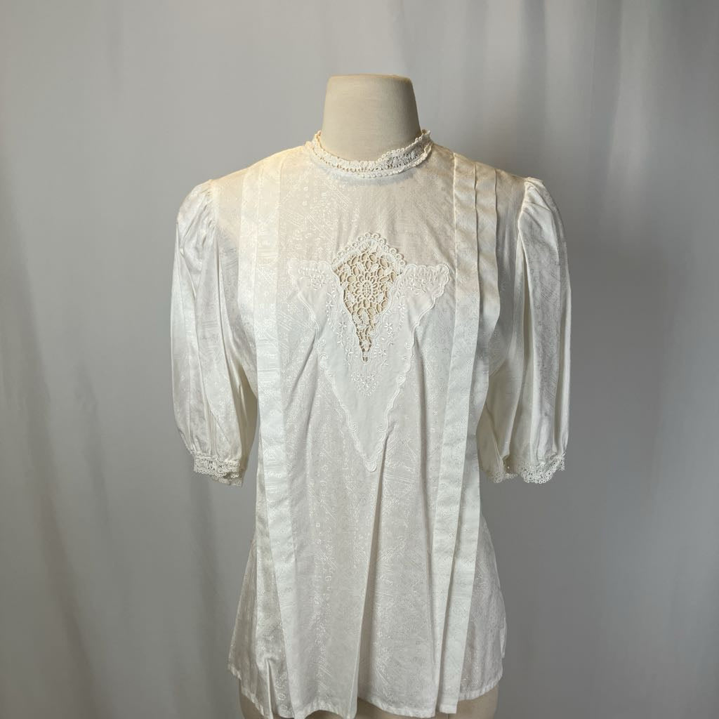 White embroidered blouse on a mannequin against a plain background