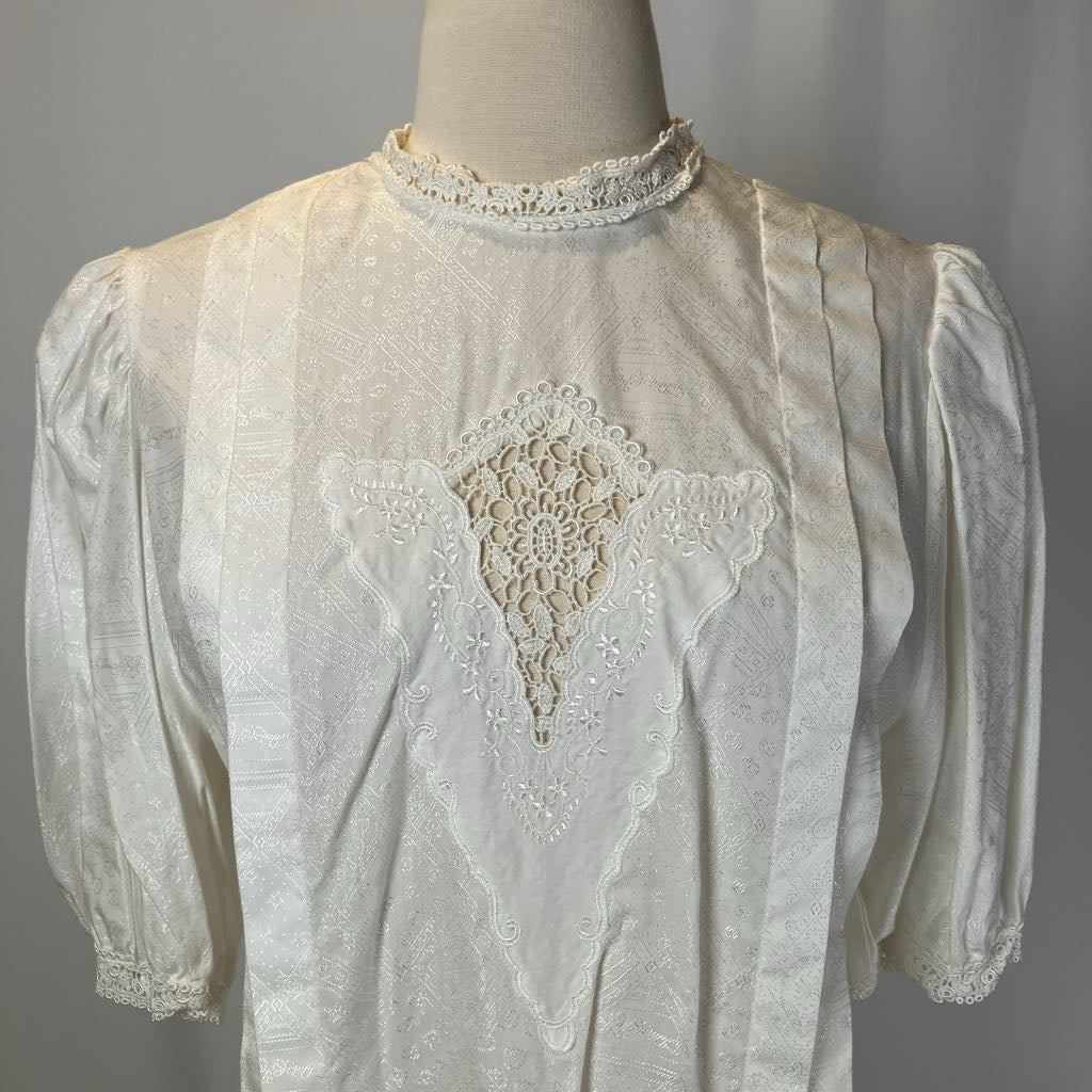 White embroidered blouse on a mannequin against a gray background