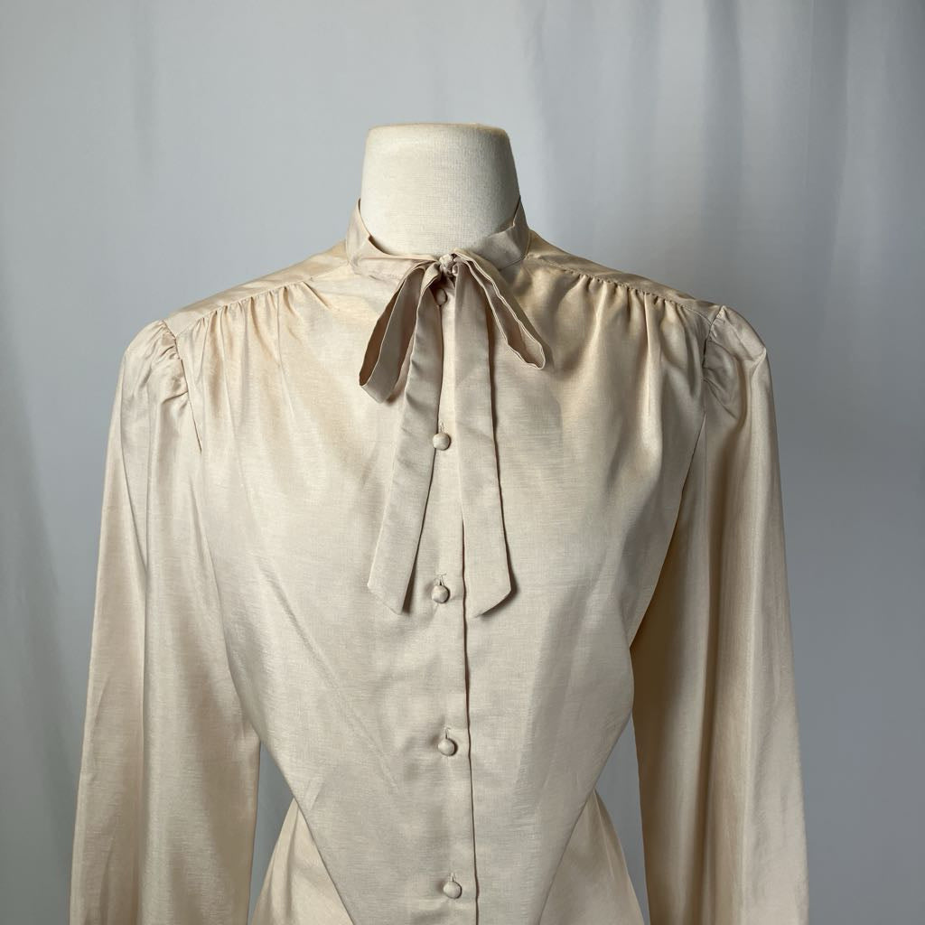 Beige blouse with a tie neckline on a mannequin against a plain background